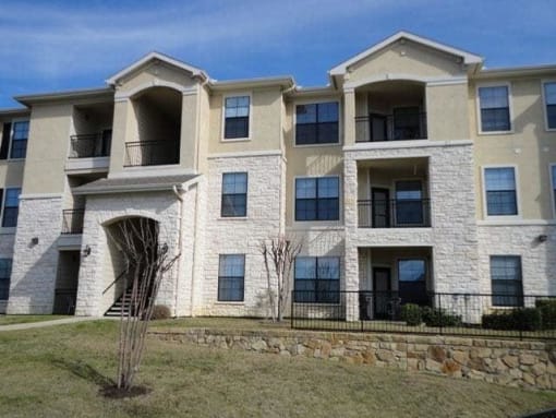 a white brick apartment building with a grass yard