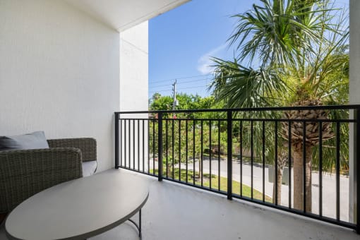 a balcony with a table and chairs and a palm tree