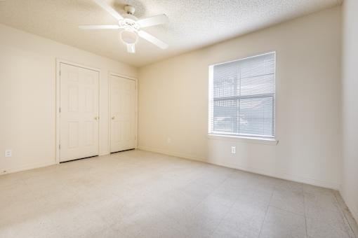 Empty room with a ceiling fan and a window.