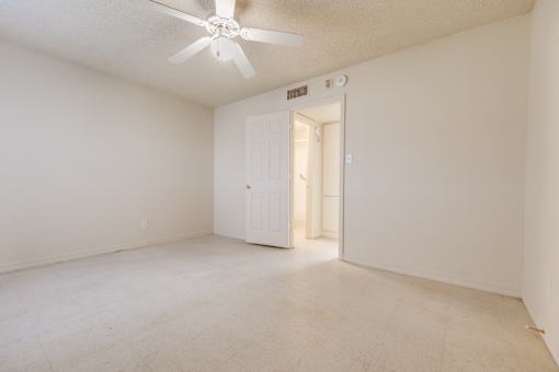A white room with a ceiling fan and a door.