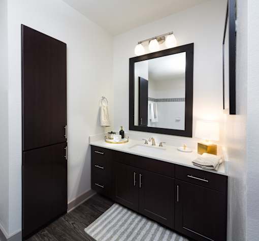 A bathroom with a sink, mirror, and a refrigerator.