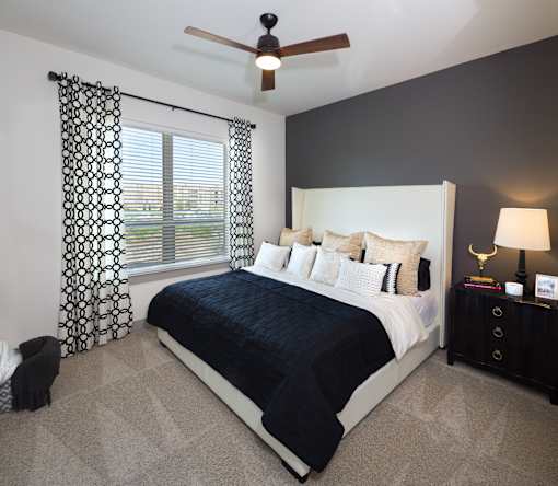 A bedroom with a large bed and a ceiling fan.