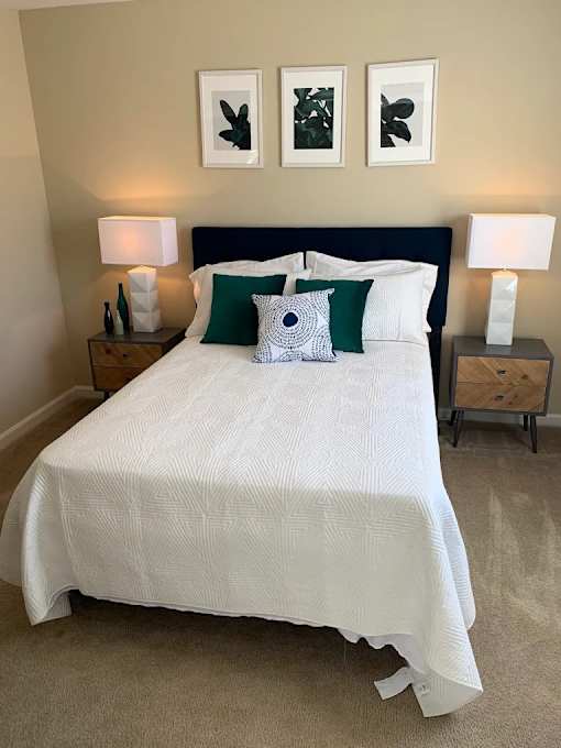 A bed with a white comforter and green pillows is in the image.