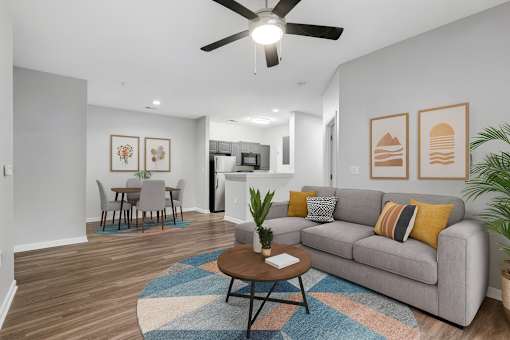 A living room with a grey couch, a coffee table, and a ceiling fan.