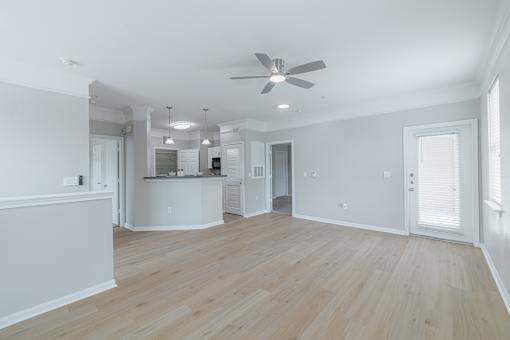 A spacious room with a ceiling fan and wooden flooring.