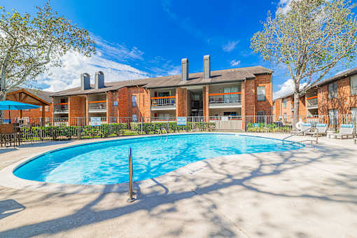 A large swimming pool in front of a red brick building.
