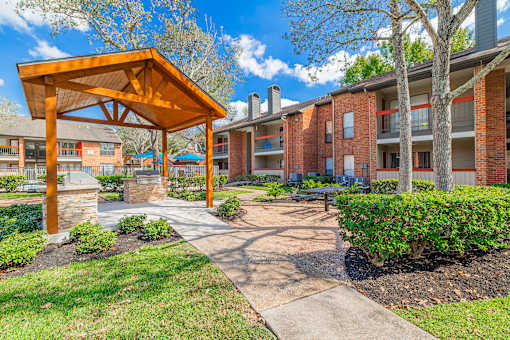 A wooden pavilion is in front of apartment buildings.