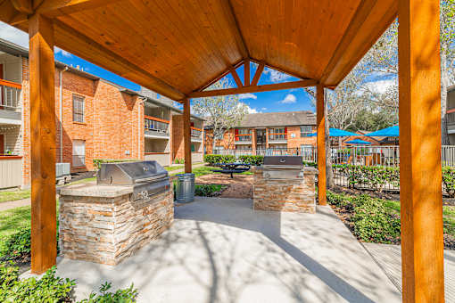 A wooden pergola with a stone fireplace underneath it.