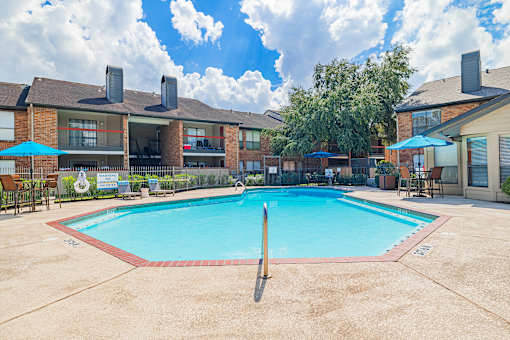 A swimming pool surrounded by a fence and chairs.