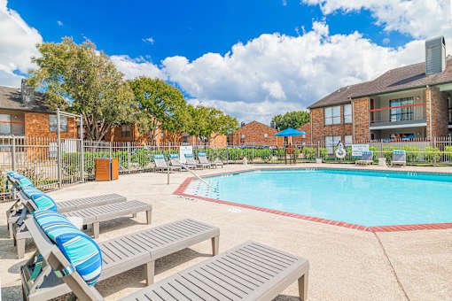 A pool area with sun loungers and a fence.