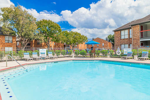 A large swimming pool surrounded by lounge chairs and trees.
