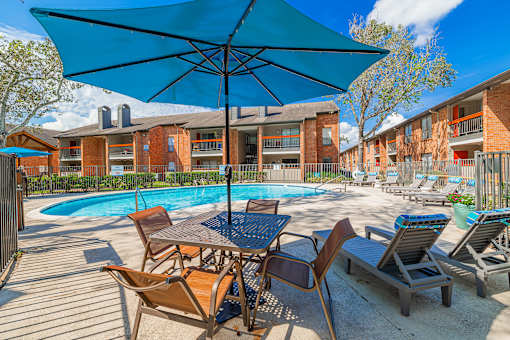 A blue umbrella is over a table with chairs around it.