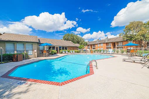 A large swimming pool surrounded by a fence and a building in the background.