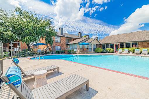 A pool with a bench and a tree in front of a house.