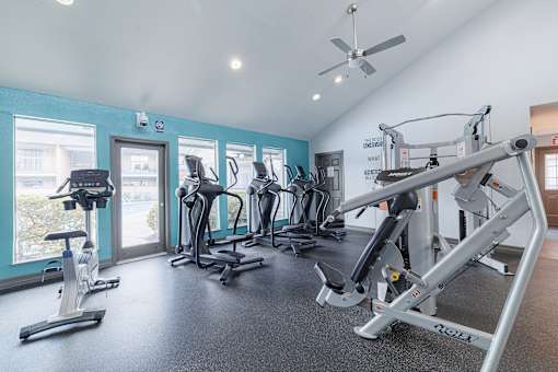 A gym with a variety of exercise equipment including treadmills, stationary bikes, and weight machines.