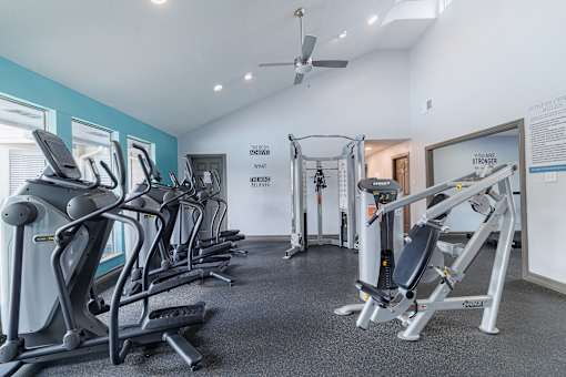 A gym with a variety of equipment including treadmills, weights, and a bench press.