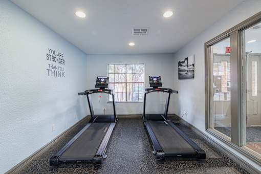Two treadmills in a room with a motivational quote on the wall.