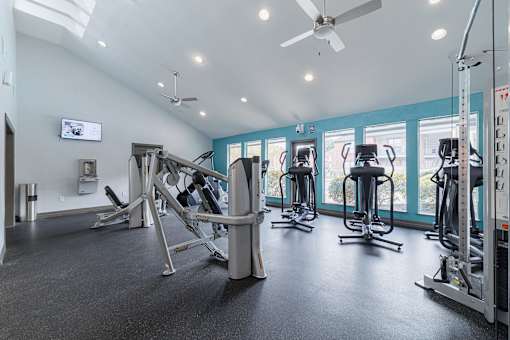 A gym with a variety of equipment including weights and a television.