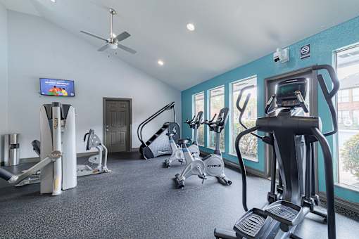 A gym with a variety of equipment including treadmills, stationary bikes, and weight machines.