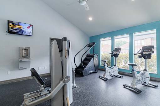 A gym with a row of stationary bikes and a treadmill.