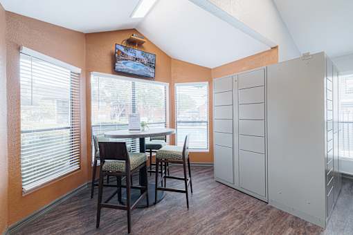 A room with a table and chairs and a television on the wall.