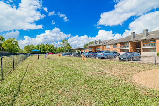 A sunny day at the apartment complex with cars parked in the parking lot.
