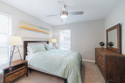 A bedroom with a bed, nightstand, and a ceiling fan.