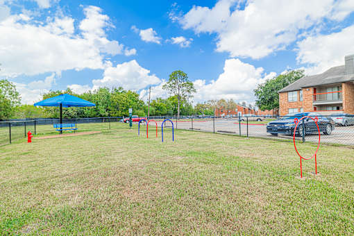 A playground with a blue umbrella and red swing set.