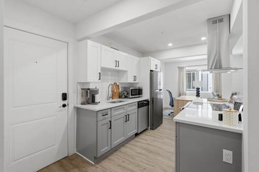A modern kitchen with a white countertop and stainless steel appliances.