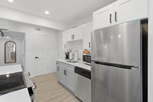 A modern kitchen with a stainless steel refrigerator and white cabinets.