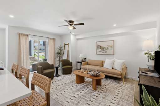 A living room with a white ceiling fan and a rug on the floor.