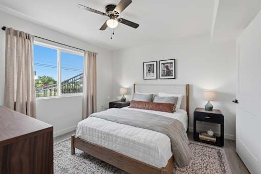 A bedroom with a large bed and a ceiling fan.