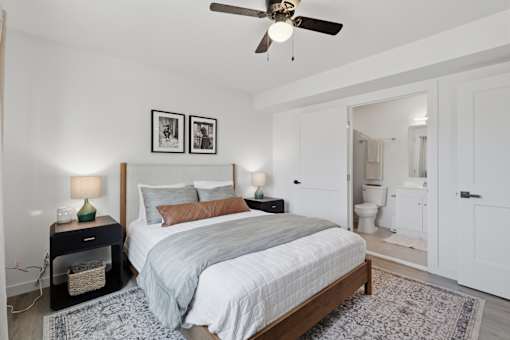 A bedroom with a bed, nightstands, and a ceiling fan.