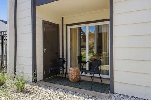 A patio with a chair and table outside a house.