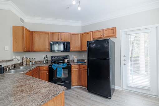 A kitchen with black appliances and wooden cabinets.