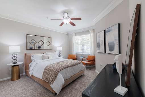 A bedroom with a bed, chair, and a painting on the wall.