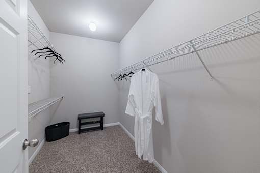 A white robe is hanging on a rack in a small, carpeted room.