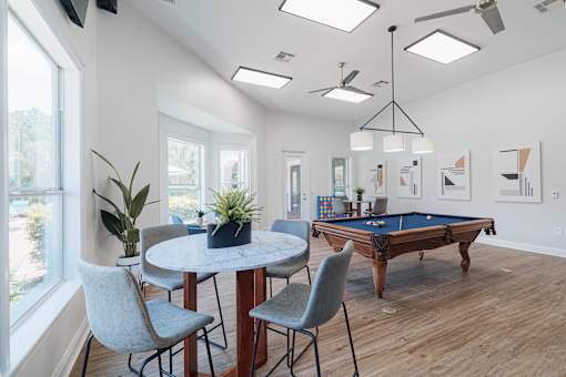A room with a pool table and a dining table with chairs.