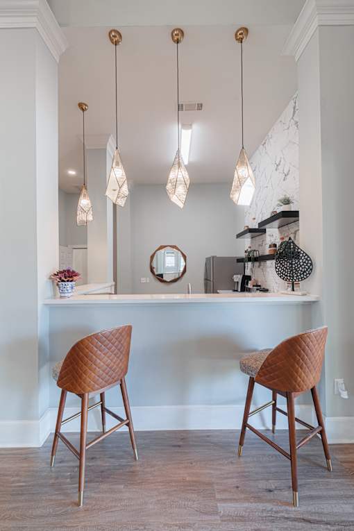 Two brown chairs are in front of a white desk with a mirror and some decorations.