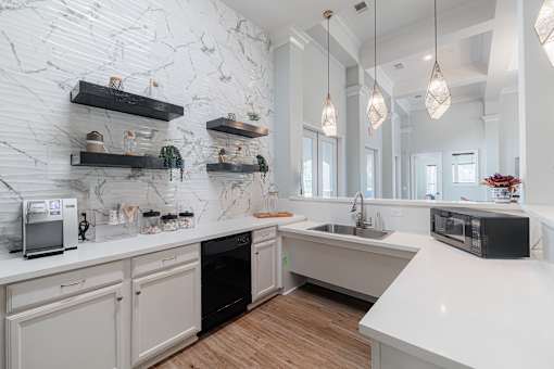 A kitchen with white marble walls and wooden floors.