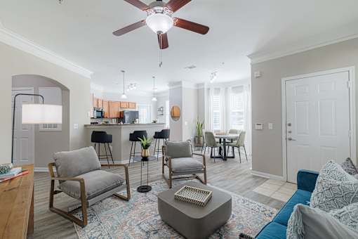 A living room with a ceiling fan and a rug on the floor.