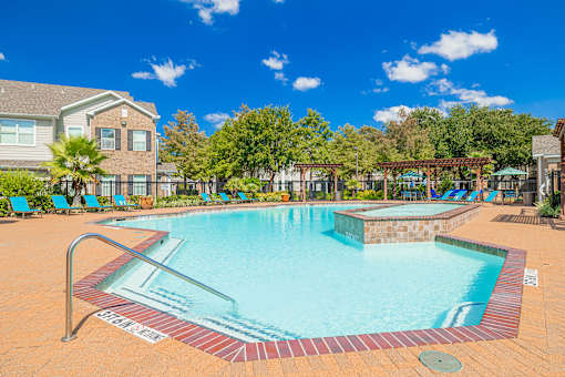 A large outdoor swimming pool surrounded by a brick border.