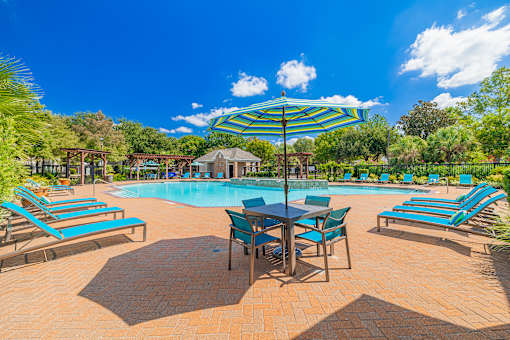 A sunny day at the pool with blue loungers and a table set up for relaxation.
