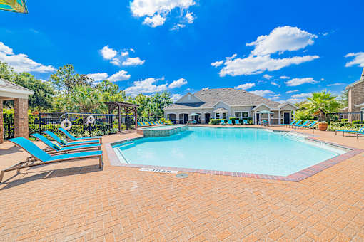 A large outdoor swimming pool surrounded by a brick patio.