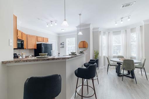 A kitchen with a bar area and a dining table with chairs.