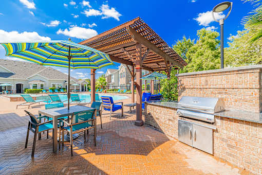 A patio with a table and chairs under a striped umbrella.