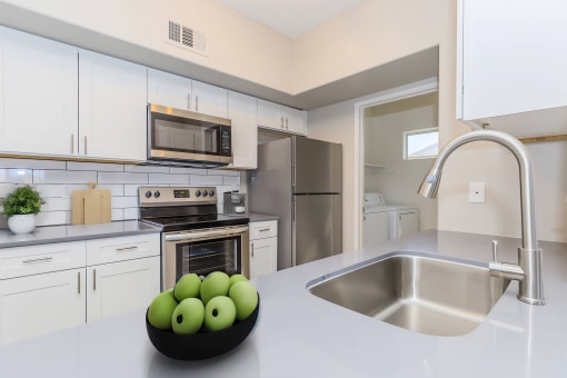 a kitchen with stainless steel appliances and a bowl of apples
