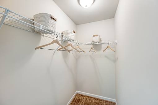 A white closet with clothes hanging on a rack.