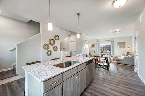 A modern kitchen with a white countertop and wooden floors.