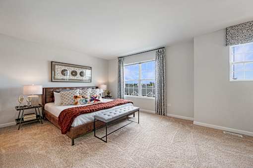 A bedroom with a large bed and a window with curtains.